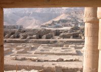Dans cette image, vue vers l’ouest de la partie centrale du sanctuaire du Ramesseum, on reconnaît, au premier plan, la porte d’accès à la salle dite des litanies ainsi que deux des colonnes encore en place dans la partie nord de la salle. Au second plan, l’emplacement du sanctuaire proprement dit est aisément reconnaissable grâce aux cavités, creusées dans le gebel et destinées à accueillir les fondations des piliers qui soutenaient le plafond ; une troisième petite salle hypostyle prenait place entre la salle des litanies et le sanctuaire.
Une terrasse aménagée à la troisième Période Intermédiaire derrière le monument, sur la voie dallée qui desservait les annexes du temple, construites en briques de terre crues, domine l’ensemble des tranchées de fondation.
Enfin à l’arrière-plan, figure les constructions, aujourd’hui détruites, du village de Cheikh Abd el-Gournah avec en toile de fond la Montagne thébaine.
 © Guy Lecuyot